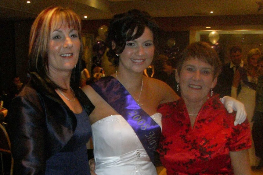 A woman, a teenage girl and an older woman pose together at a formal function.