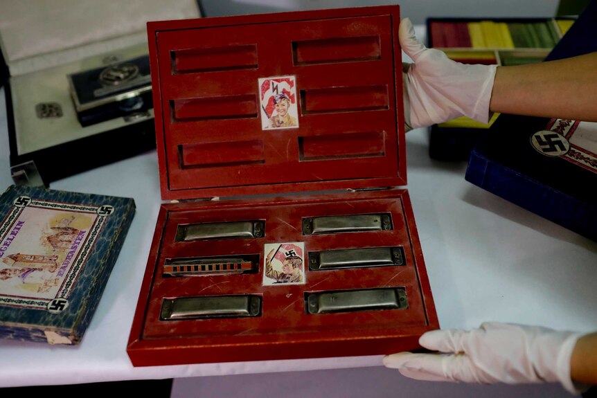 A member of The federal police shows a box with swastikas containing harmonicas for children at the Interpol HQ.