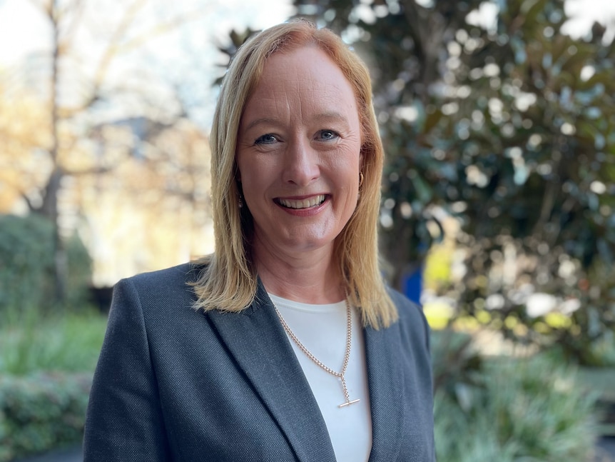 Carol Hodgson wearing a grey suit jacket and smiling at the camera.