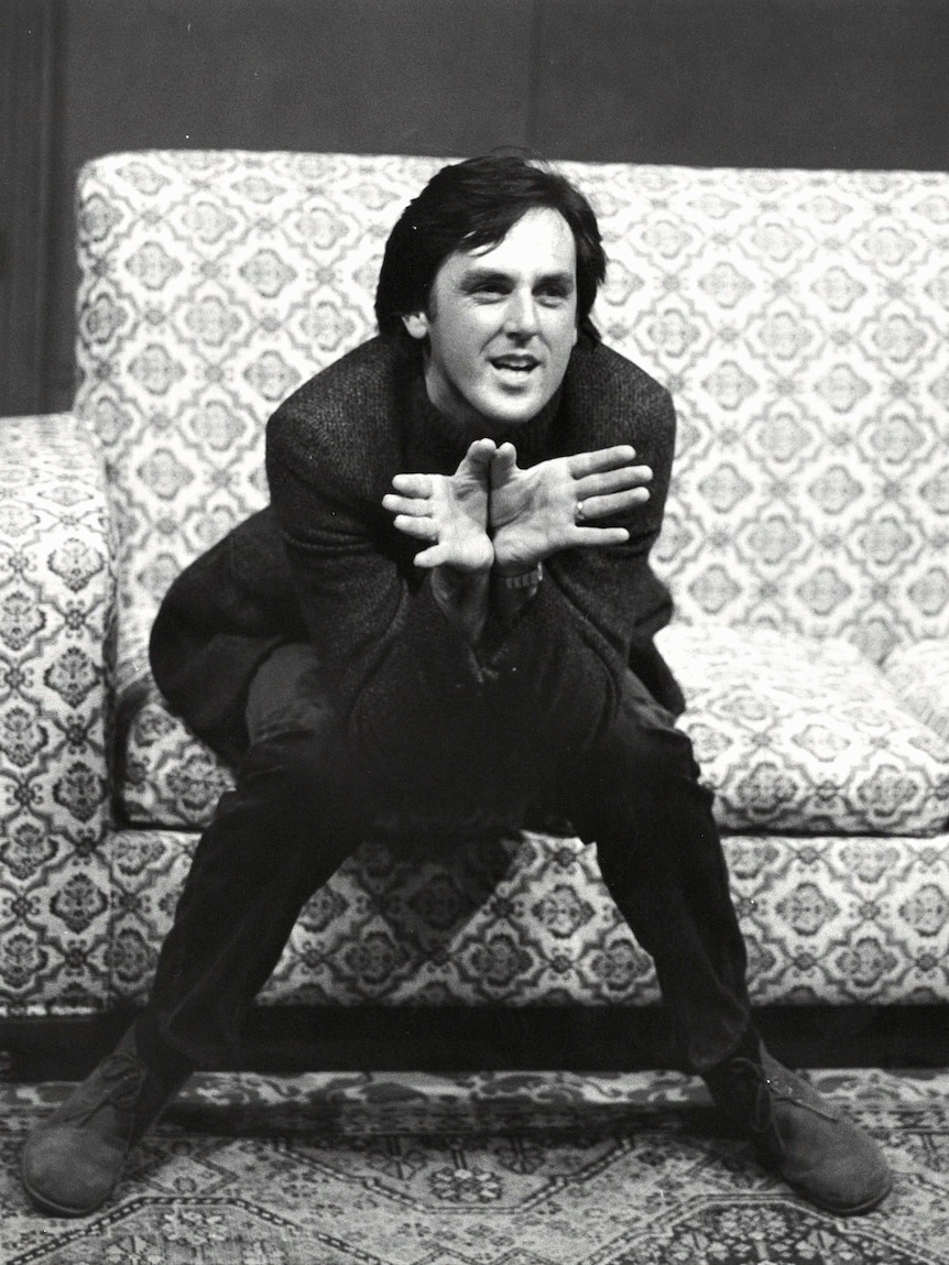 A 1982 photograph of John Doyle sitting on a couch on stage