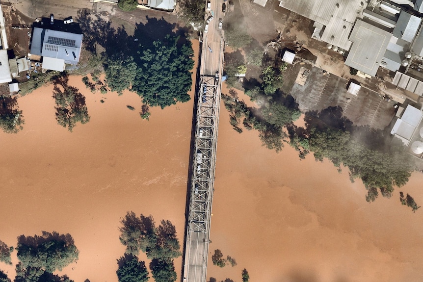 An aerial view of a bridge over a swollen river. 