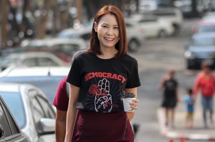 Young woman wearing red skirt and black t-shirt holds coffee cup