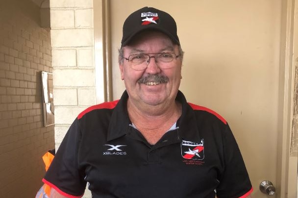 A man poses for a photo wearing a black and red uniform shirt and hat