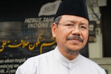Hizbut Tahrir's Indonesian spokesman Ismail Yusanto stands in front of a sign promoting HTI