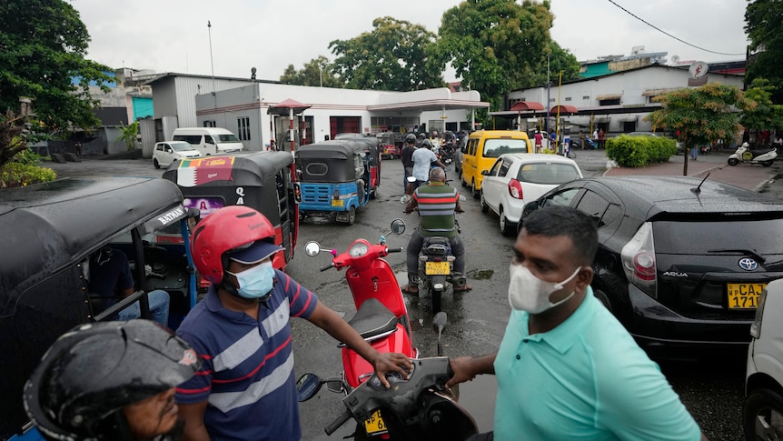 People wait in a long queues to buy fuel for their vehicles at a petrol station