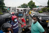 People wait in a long queues to buy fuel for their vehicles at a petrol station