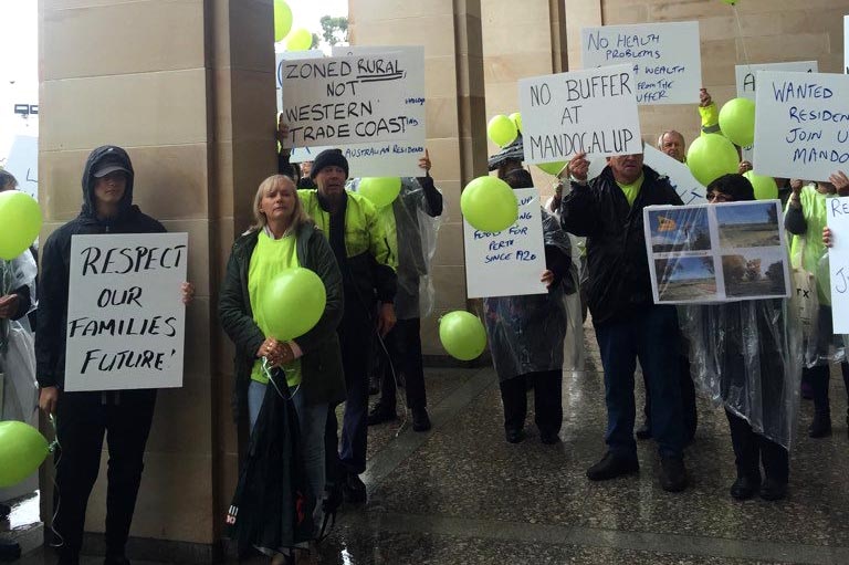 Protesters hold placards and balloons outside Parliament House.