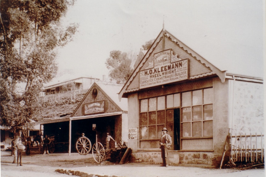 an old photo of a building with a man in a hat standing outside the front door
