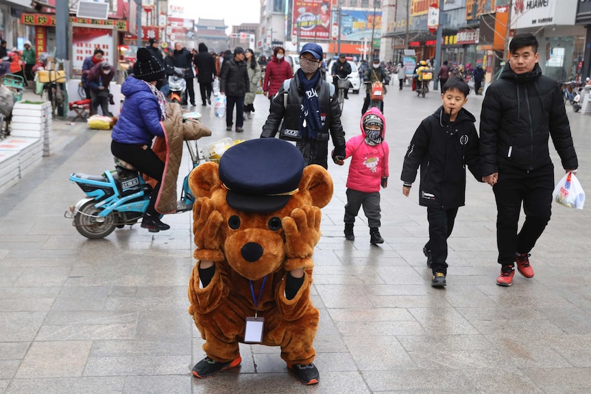 A promoter dressed as a teddy bear rests along a retail street in Zhangjiakou in northern China's Hebei province.