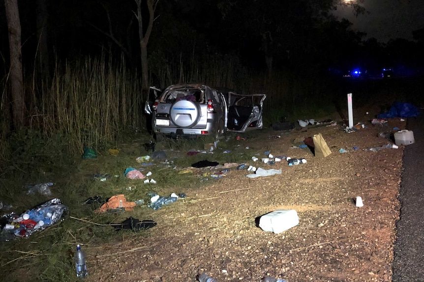 Two police officers sweep a bend in the road with debris on it.