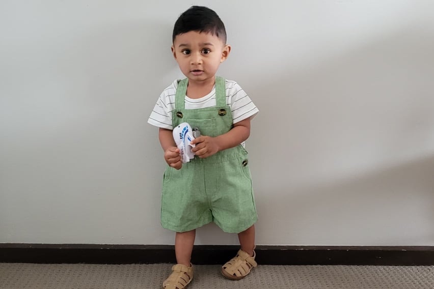 A 10-month-old Australian boy stands against a white wall.