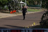 A police officer walks down the road with evidence markers around his feet