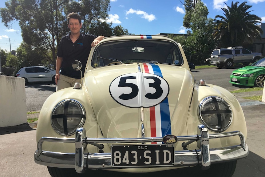 Man stands next to cream Volkswagen Beetle