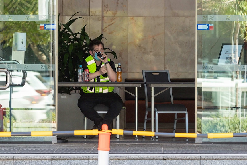 A security guard sits at the entrance to the Four Points Sheraton hotel in Perth talking on a walkie talkie.