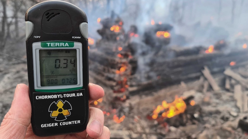 A Geiger counter shows increased radiation level against the background of the forest fire burning near Chernobyl.