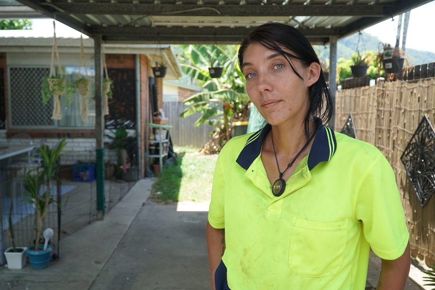 A woman in high-vis standing under her car port in a suburban house