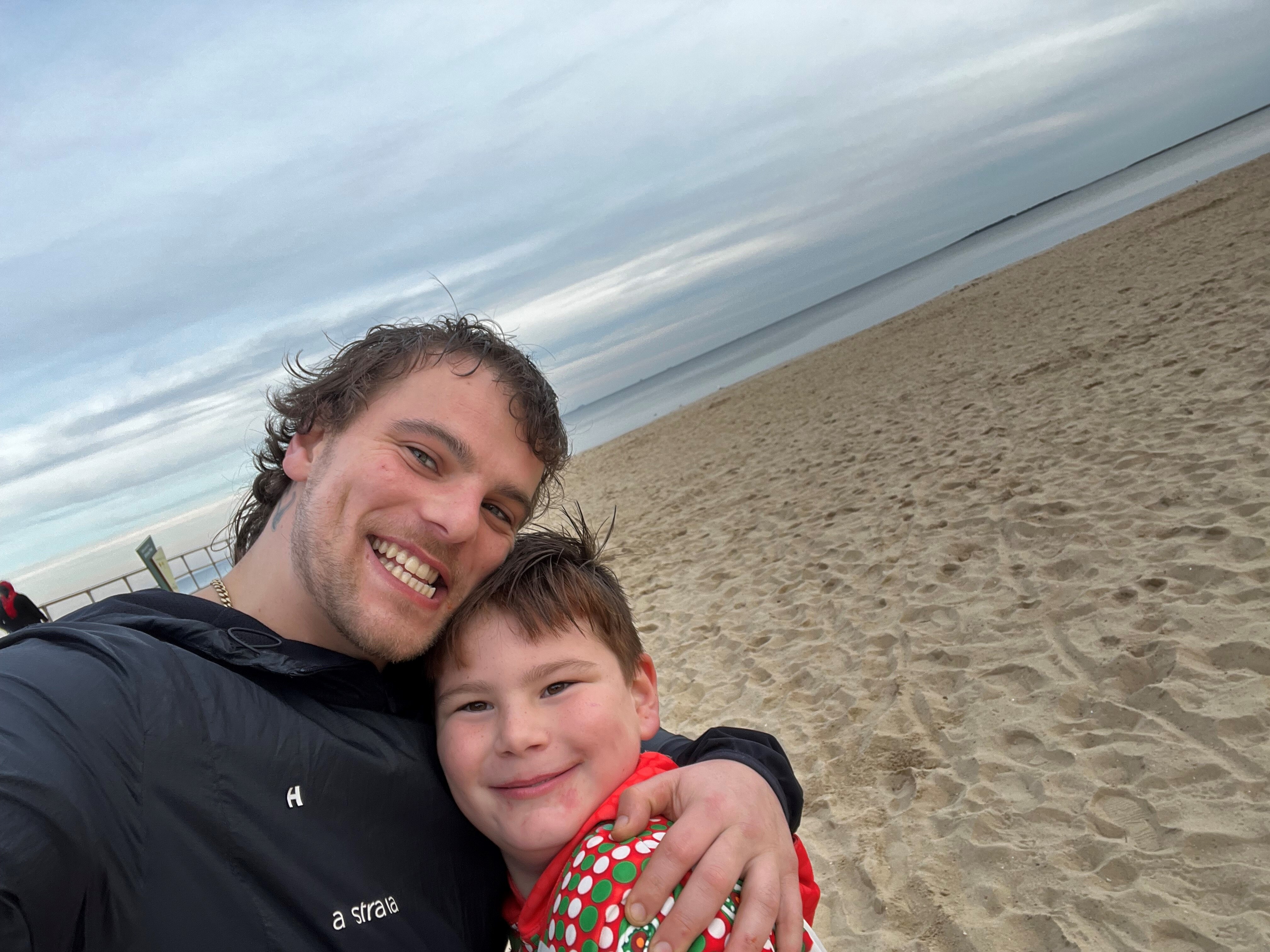 A father and a son hugging on the beach.