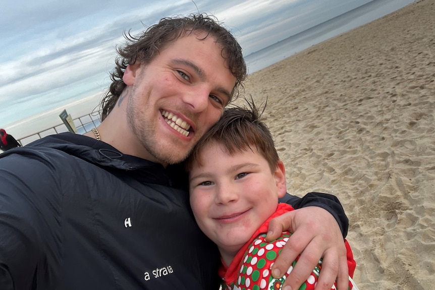 A father and a son hugging on the beach.