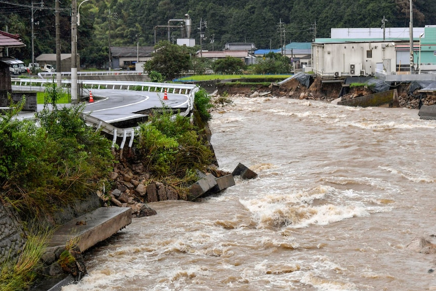 L'acqua di inondazione scorre accanto a una strada che crolla nell'acqua.