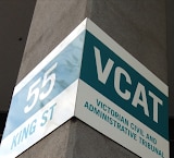 A sign with the words Victorian Civil and Administrative Tribunal hangs on a concrete pillar