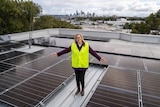 Town of Victoria Park Mayor Karen Vernon stands on top of solar panels with her arms outstretched.