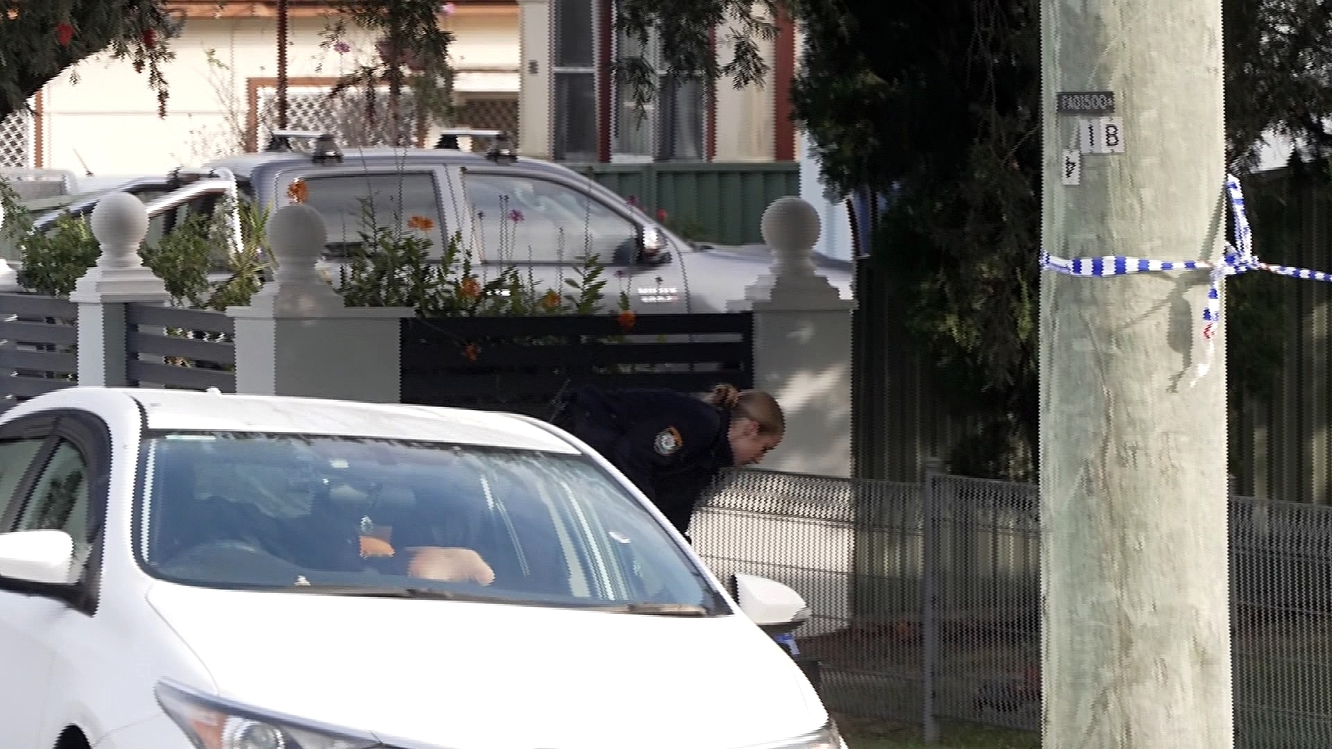 a police officer inspects the ground on Orchardleigh Street in Yennora after a man was found with head injuries