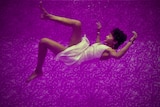 A sleeping woman falls through a purple background