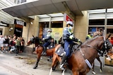 uniformed police wearing face masks on horseback are confronted by a group of anti-lockdown protesters in Sydney