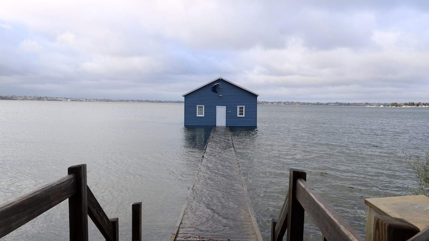 The jetty leading to the blue boathouse at Crawley submerged by heavy rain.