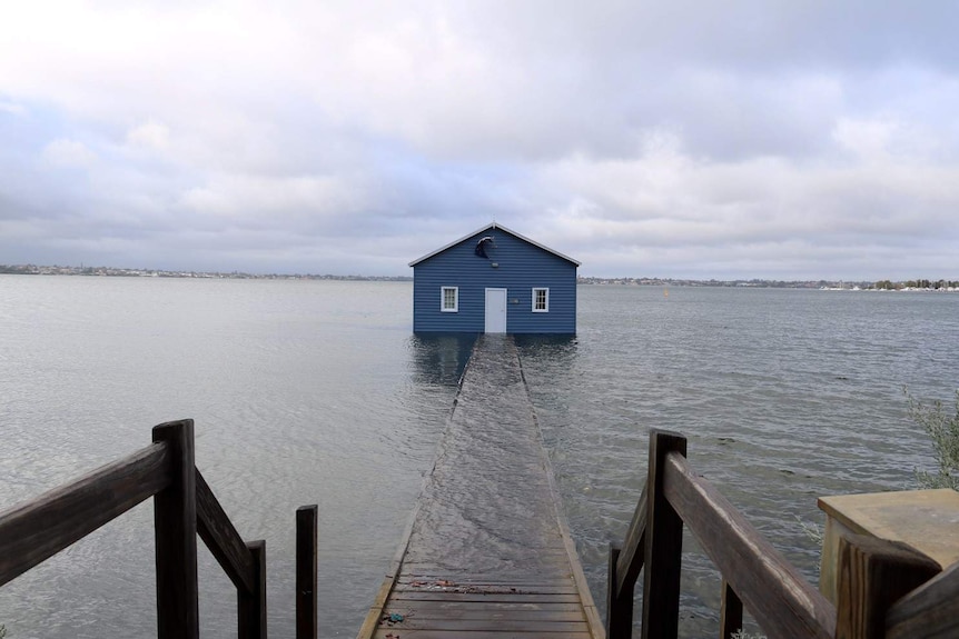 The jetty leading to the blue boathouse at Crawley submerged by heavy rain.