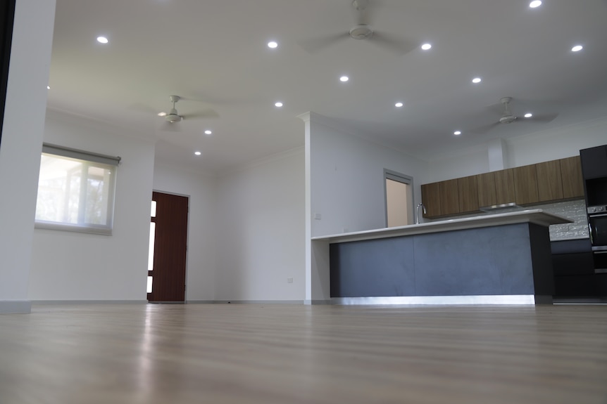 A photo showing inside of an empty house with no furniture with lights on 