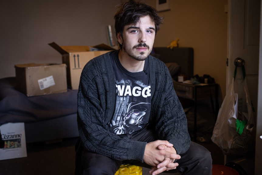 A man looks at the camera with boxes in the background.