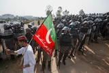 One of Imran Khan's supporters stands in front of lines of armoured police.