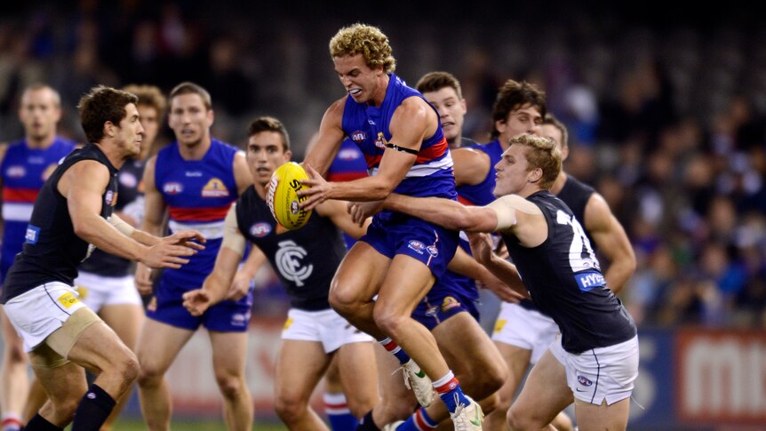 Mitch Wallis grabs the ball and holds on as the Blues close in.