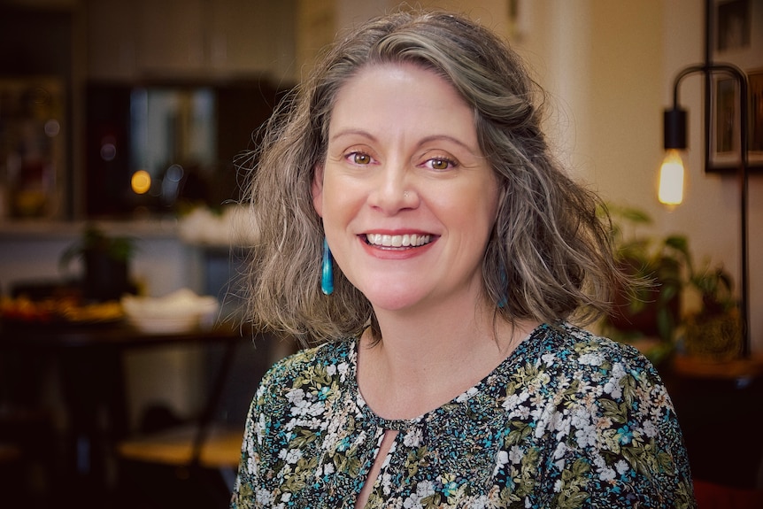 A smiling woman with brown hair in her home