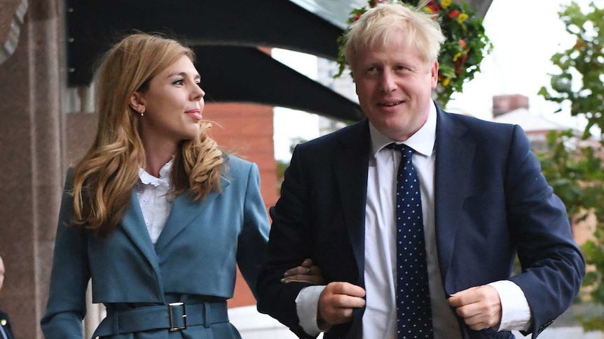 Britain's Prime Minister Boris Johnson walks arm-in-arm with partner Carrie Symonds