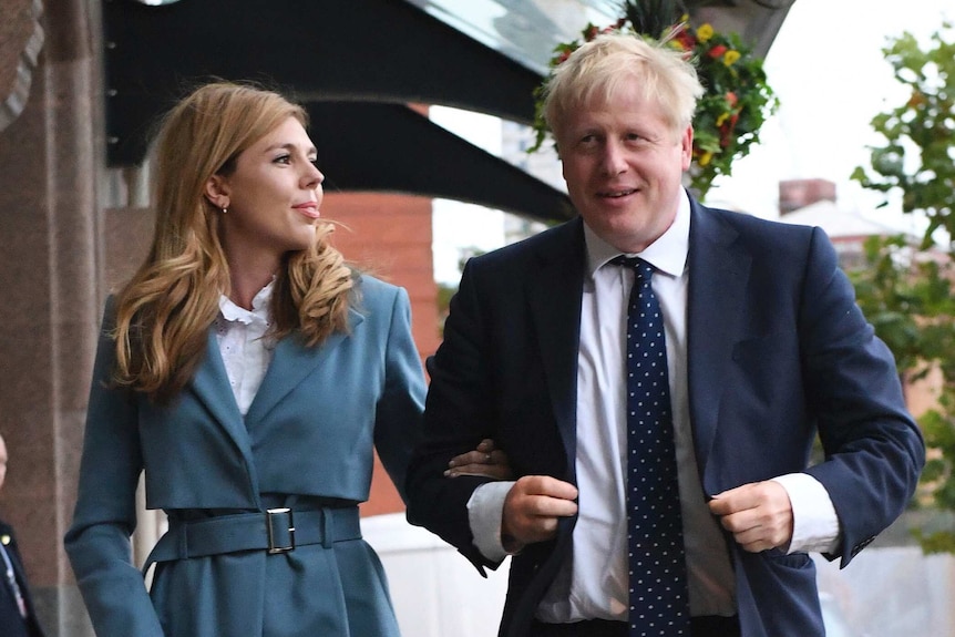 Britain's Prime Minister Boris Johnson walks arm-in-arm with partner Carrie Symonds