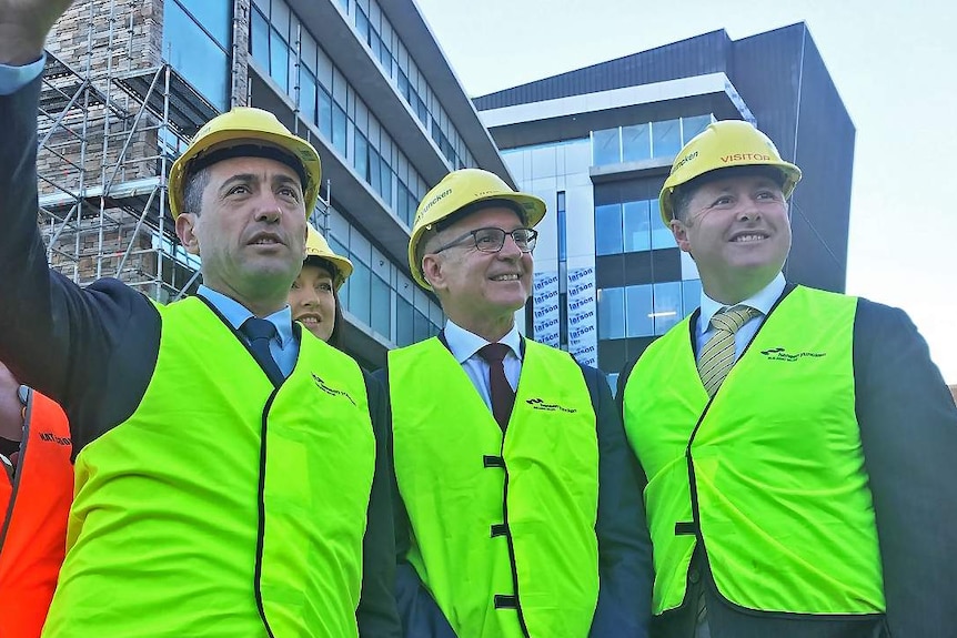 Four politicians stand in front of a building development
