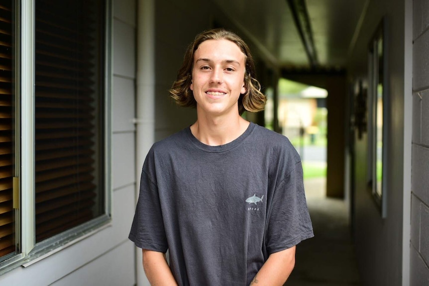 Young man standing at end of walkway to his home.