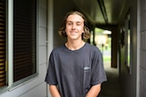 Young man standing at end of walkway to his home.