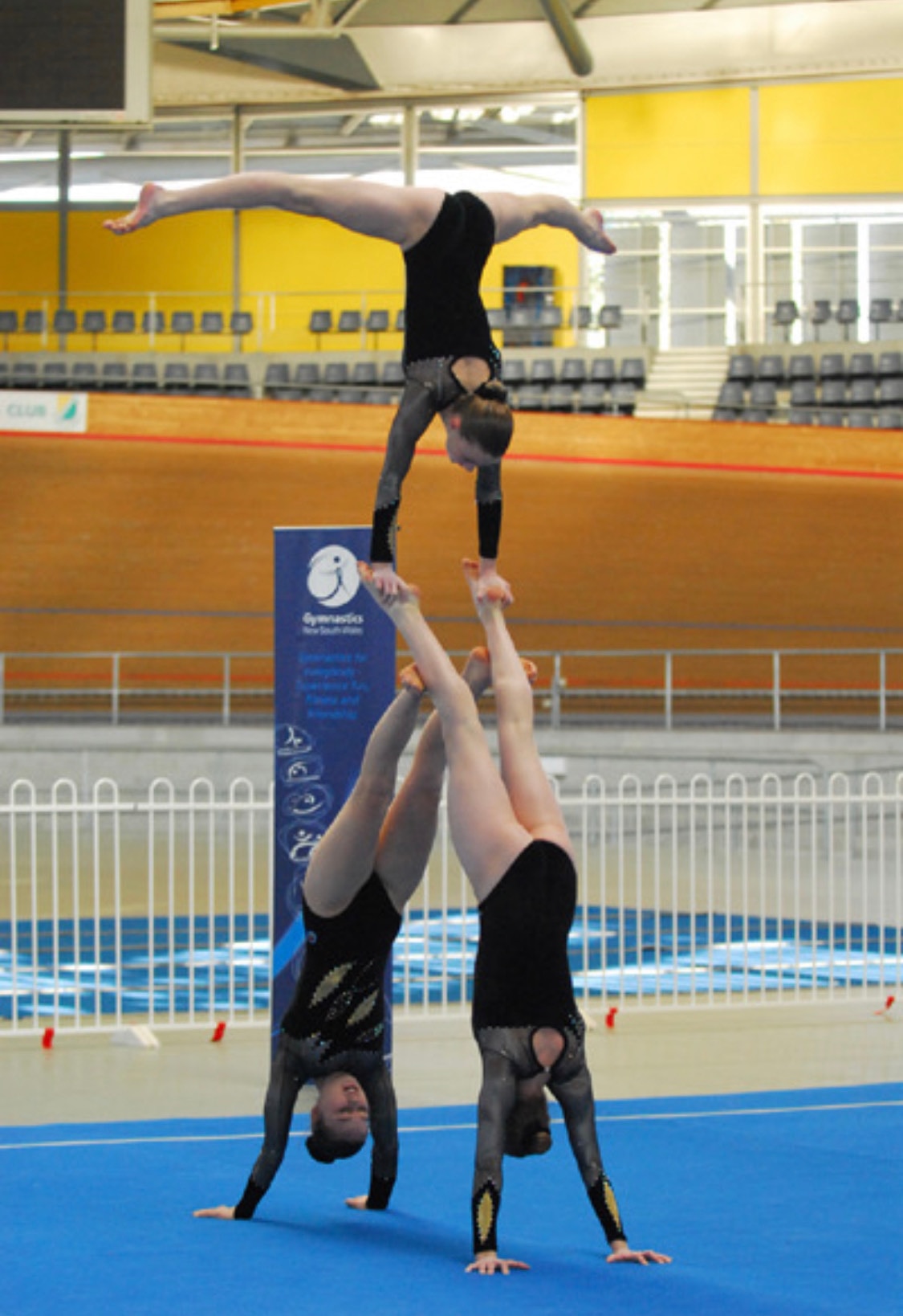 A photo of three gymnasts performing an acrobatic routine
