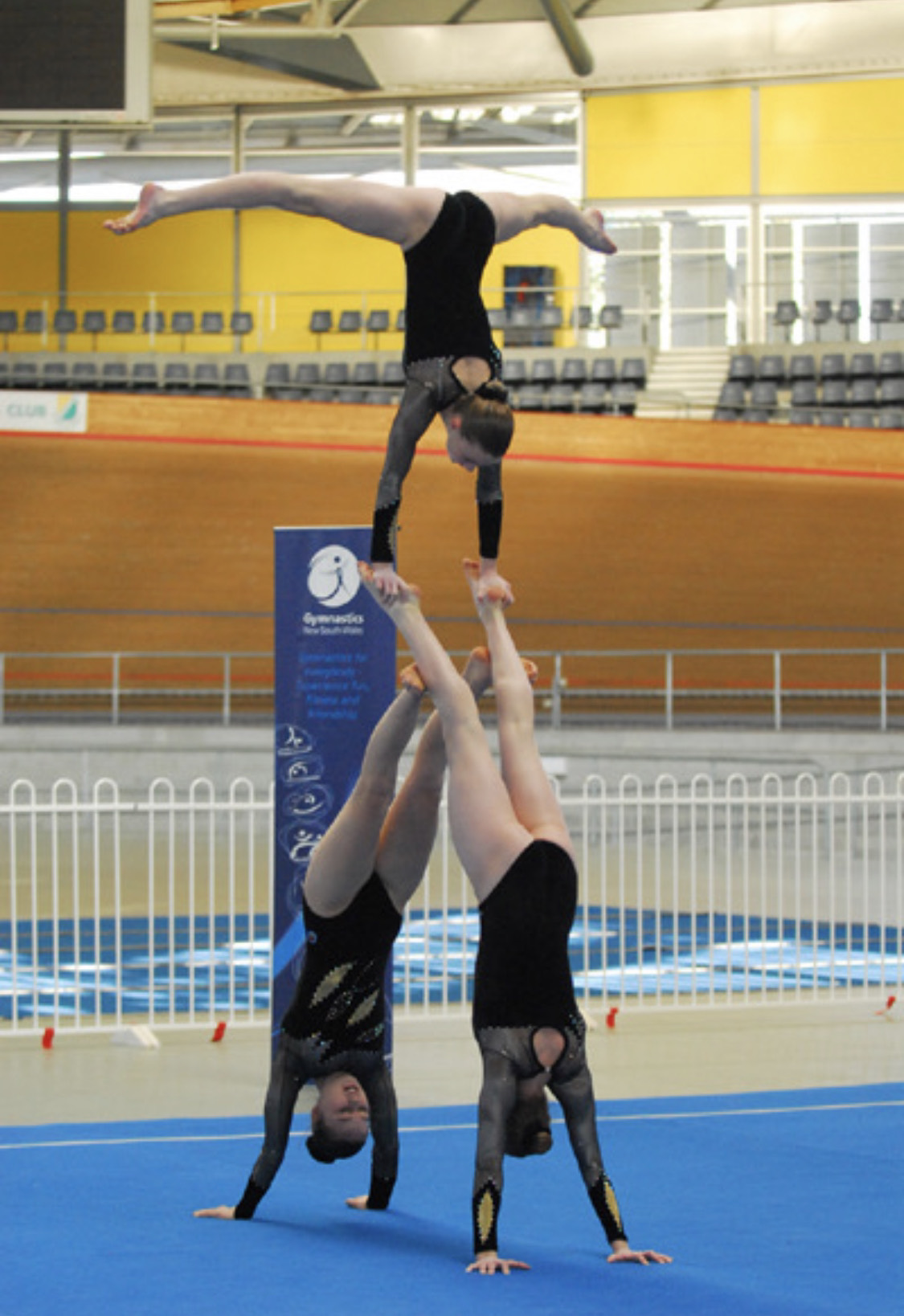 A photo of three gymnasts performing an acrobatic routine