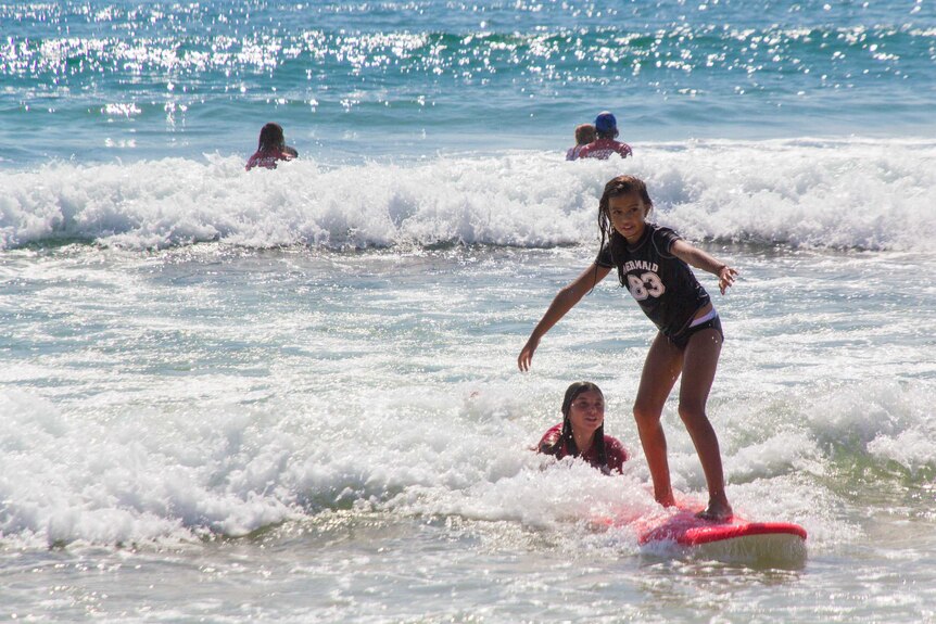 A child surfing on a pink board