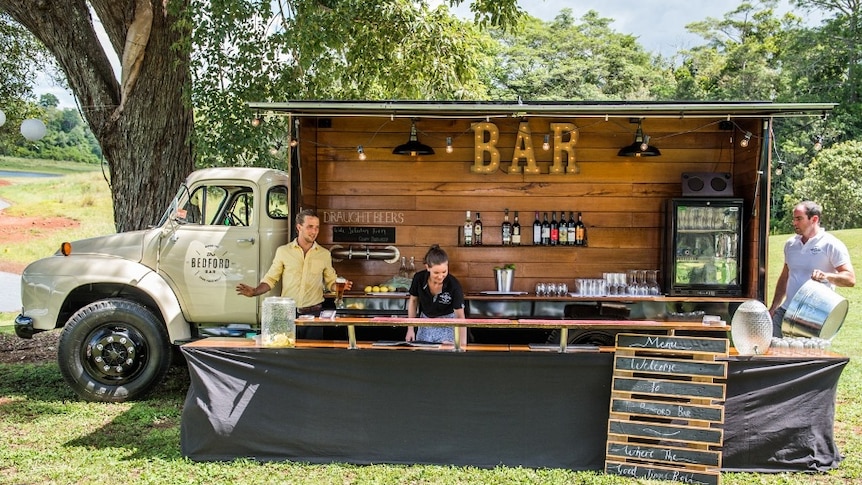 An old cream Bedford truck with a bar built into the back