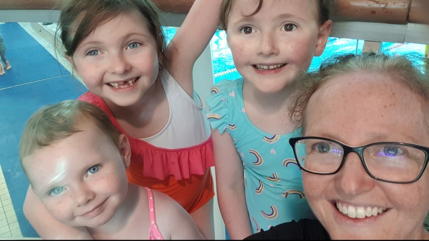 A woman on the right takes a selfie with her three young daughters