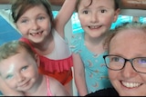 A woman on the right takes a selfie with her three young daughters