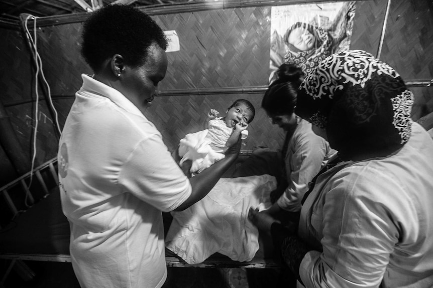 Bakoko Matua, a midwife from Uganda, holding a baby.