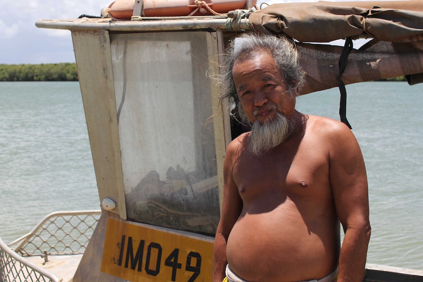 a man standing on his boat with the river in the background.