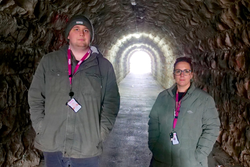 A man and woman stand inside a tunnel.