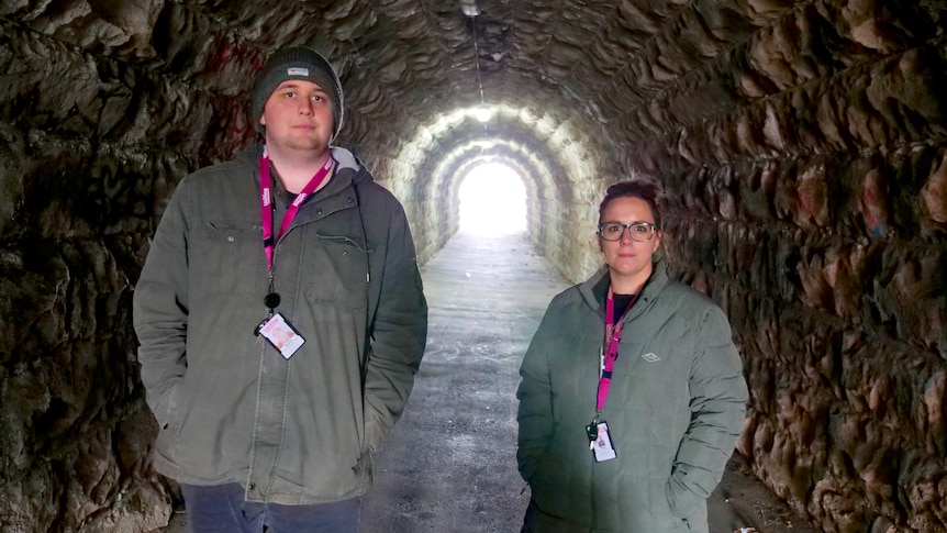 A man and woman stand inside a tunnel.